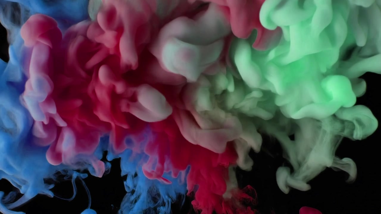 Nuvole d'inchiostro colorate vorticose nell'acqua su sfondo nero