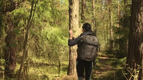 Hiking-woman-walk-with-a-hiking-backpack-in-spring-green-forest