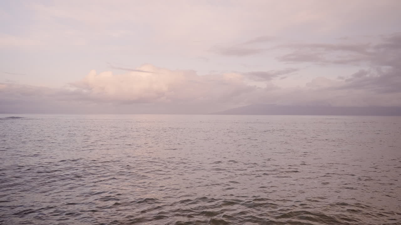 백그라운드에서 산 실루엣으로 일몰 후 모래 해변에서 씻는 파도의 개요