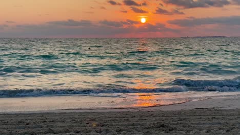 vibrant sunset over ocean waves with sandy beach in foreground