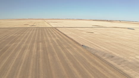 Big-semi-truck-leaves-field-with-harvest,-tracking-long-drone-shot