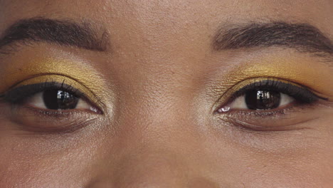 close up african american woman eyes wearing makeup looking happy at camera blinking beauty cosmetics