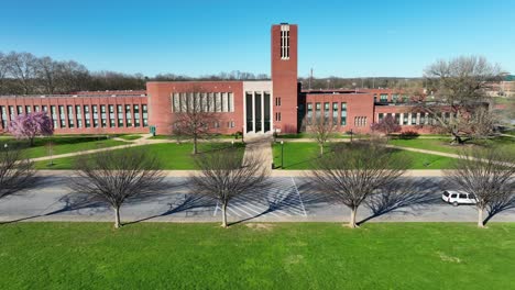 Traffic-on-road-in-front-of-american-high-school-during-sunny-day-in-spring-season