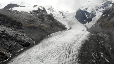 sobrevuelo aéreo sobre el glaciar morteratsch en engadin, suiza, con algunos de los picos más altos de los alpes suizos como piz bernina, piz palu escondido en las nubes