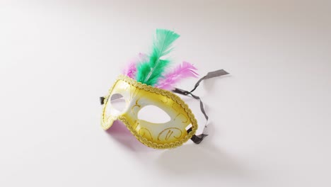 Video-of-white-and-gold-masquerade-carnival-mask-with-green-and-pink-feathers-on-white-background