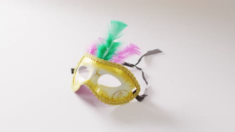 video of white and gold masquerade carnival mask with green and pink feathers on white background