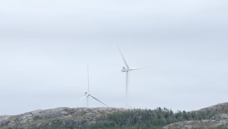 hildremsvatnet, condado de trondelag, noruega - un molino de viento situado en la cima de una colina, rodeado de árboles de coníferas - toma amplia