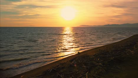 Imágenes-Cinematográficas-épicas-De-Drones-Aéreos-De-La-Puesta-De-Sol-En-Una-Playa-De-Arena-En-La-Costa-Cerca-De-Alberese-En-El-Icónico-Parque-Natural-Maremma-En-Toscana,-Italia,-Con-Olas,-Islas-Y-Un-Espectacular-Cielo-Rojo