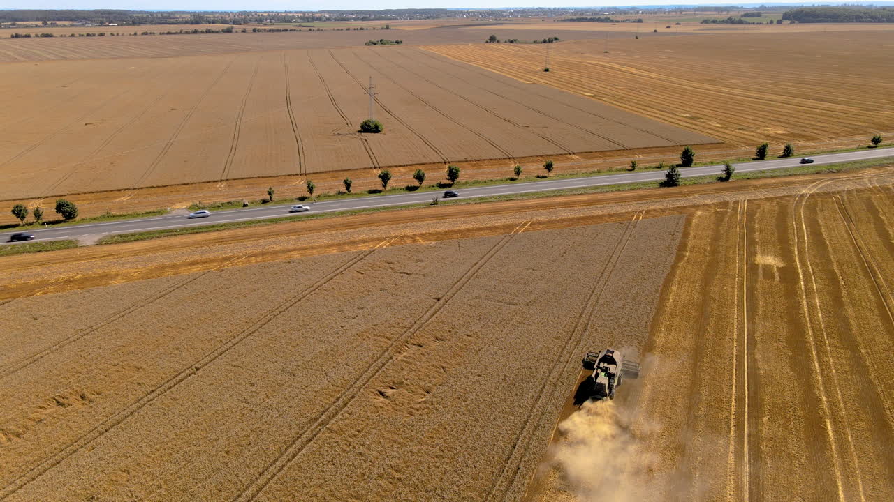 Cars Driving On The Country Road With A Farming Tractor Harvesting Ripe And Golden Crops On The Field In Puck, Poland. - aerial drone shot