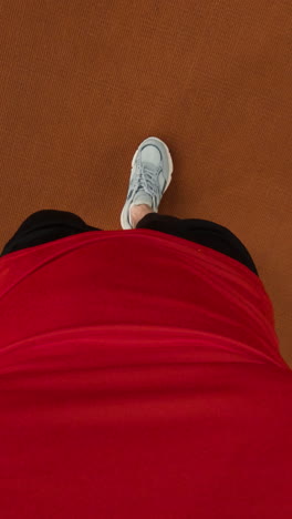 person in red shirt and shorts with sneakers, shot from above
