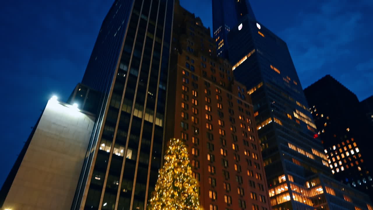 Nova Iorque, EUA, 2 de Dezembro de 2025: Linda árvore de Natal decorada com bolas douradas e luzes. Edifícios altos de Nova Iorque ao fundo.