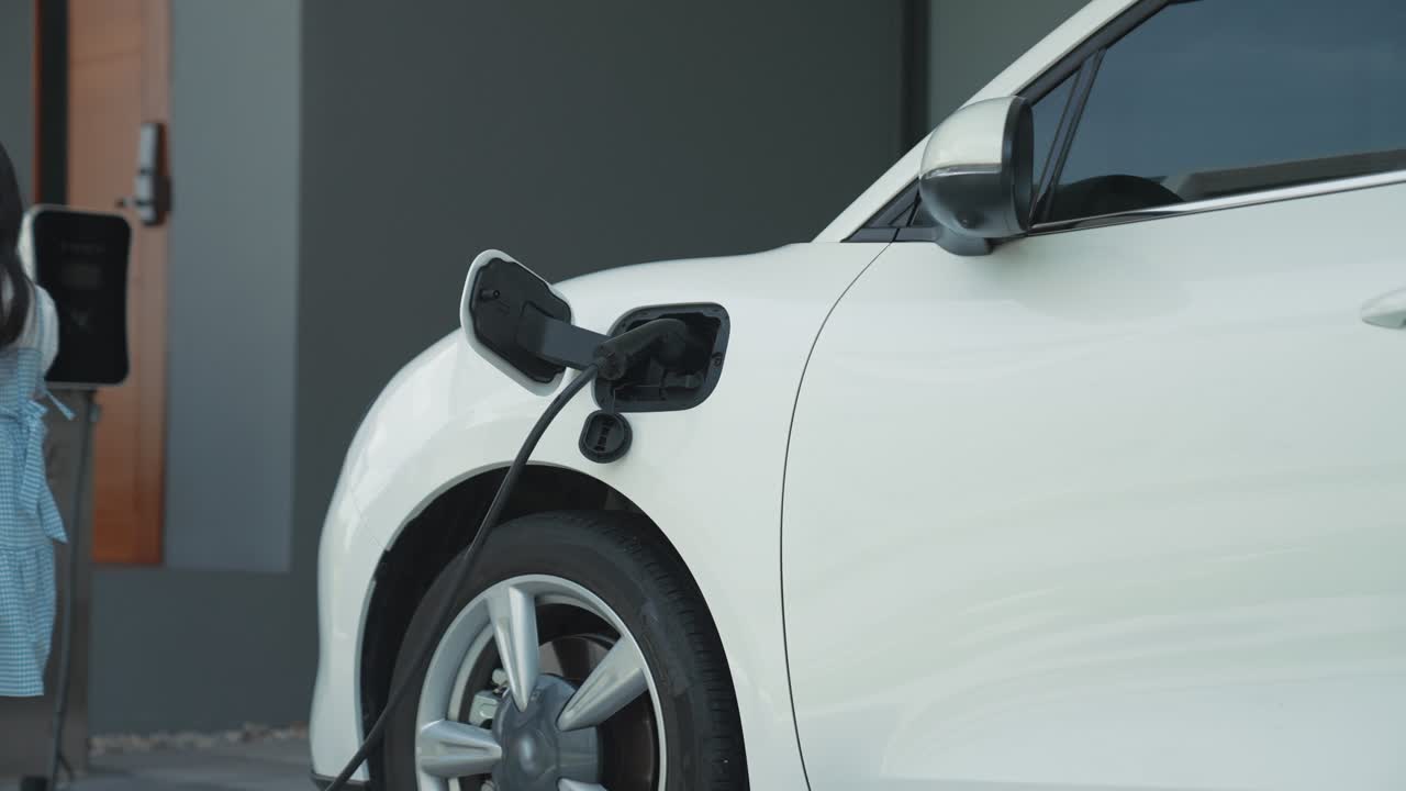 Ev şarj istasyonundan elektrikli araç şarj eden ilerici baba ve kızı