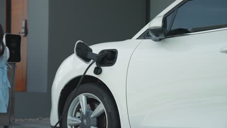 Progressive-dad-and-daughter-charging-EV-car-from-home-charging-station.