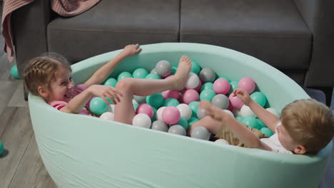 joyful children have fun in pool with balls in living room