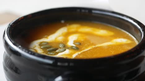 close-up of a bowl of pumpkin soup with cream and pumpkin seeds