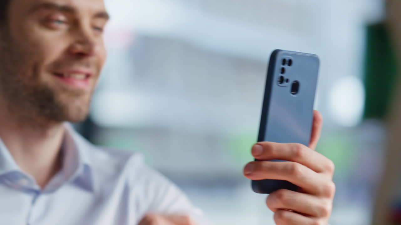 Businessman hands holding mobile phone in office closeup. Smiling man tapping