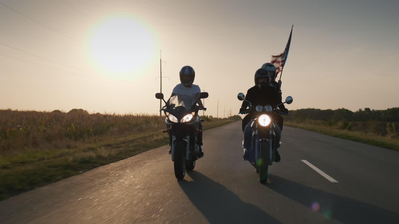 un par de ciclistas viaja en una motocicleta seguido de una bandera americana 1