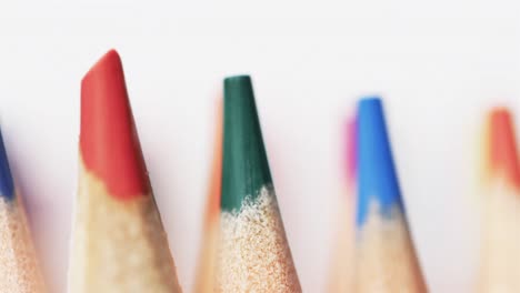 Close-up-of-colourful-pencil-crayons-on-white-background,-in-slow-motion