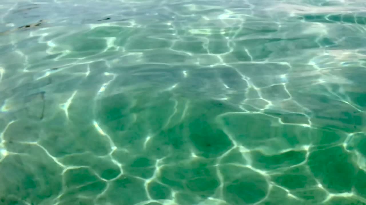 cámara lenta de la superficie de agua de mar transparente y translúcida cristalina con suelo de arena blanca y ondas