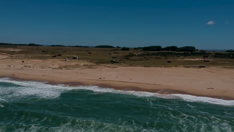 Drohne-Fängt-Natürliche-Meereswellen-Am-Küstenstrand-Von-Rocha-In-Uruguay-Ein,-Menschen,-Die-Am-Küstenstrand-Von-Rocha-In-Uruguay-Spazieren-Gehen