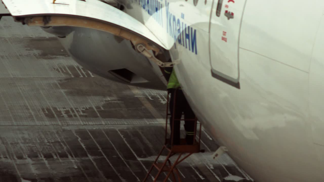 Un addetto aeroportuale è in piedi su una scala vicino a una stiva per i bagagli