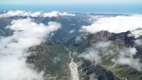 Aerial-shot-from-plane-scenic-flight-over-west-coast-Fox-Glacier-Aoraki-Mount-Cook,-National-Park-with-clouds,-snowcapped-rocky-mountains-and-ocean-in-background