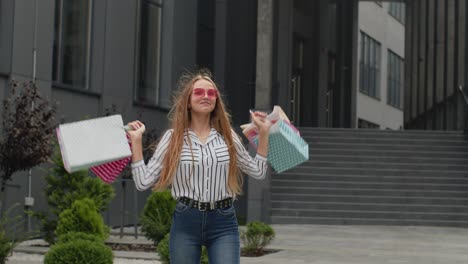 girl raising shopping bags, looking satisfied with purchase, enjoying discounts on black friday