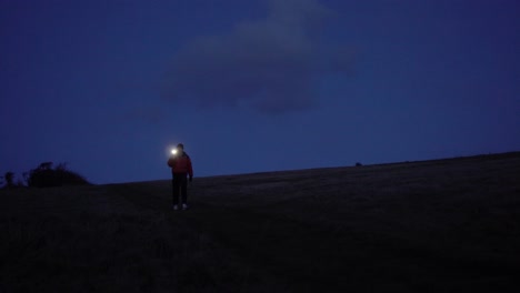 Hombre-Solitario-Caminando-Por-El-Campo-Con-Una-Linterna-Telefónica.