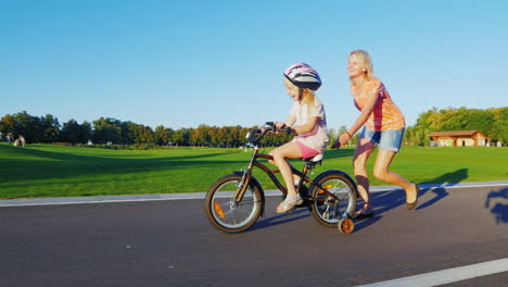 Mama-Bringt-Mädchen-Bei,-Fahrrad-Zu-Fahren-Konzept---Hilfe-Und-Unterstützung-Für-Eltern-Eine-Glückliche-Kindheit