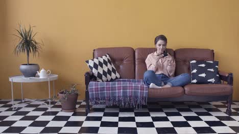 mujer relajándose en el sofá usando un teléfono inteligente