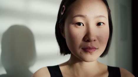 Cara-De-Hermosa-Mujer-China-Suave-Mirando-La-Cámara,-Sombra-En-El-Fondo