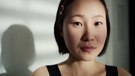 face of beautiful soft chinese woman looking at camera, shadow on background