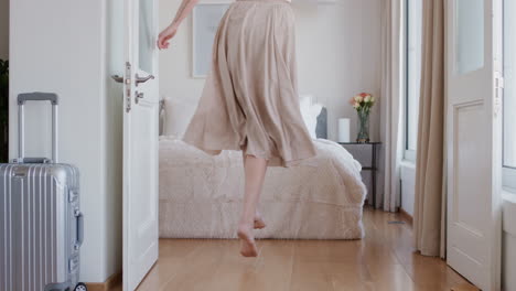 Mujer-Feliz-Saltando-En-La-Cama-En-La-Habitación-Del-Hotel-Divirtiéndose-Disfrutando-Del-Estilo-De-Vida-De-Vacaciones-Celebrando-La-Libertad