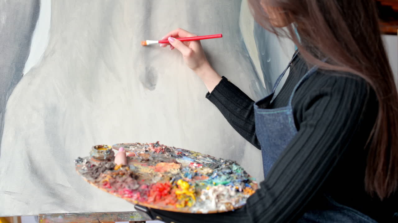 Woman painting a female body on a canvas at an art gallery workshop
