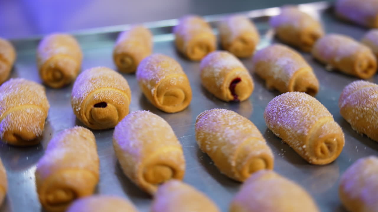 Sweet delicious freshly baked croissants sprinkled with sugar are on the tray. Tasty pastry at modern bakery. Close up.