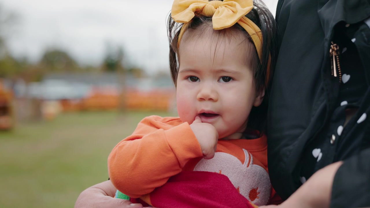 Toddler Girl Wearing Yellow Bow Held Outdoors