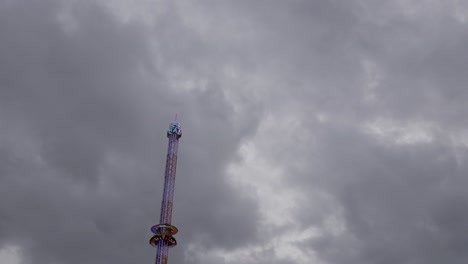 a tall drop tower against a cloudy, dramatic sky, evoking thrill and suspense