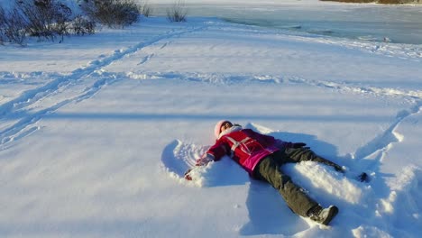 Seitenansicht-Kleines-Mädchen-Macht-Schneeengel.-Winterkind.-Sonniger-Wintertag