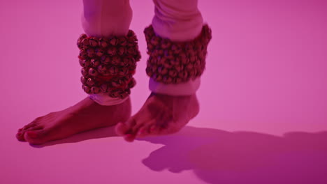 cerca de los pies y las campanas de la bailarina de kathak femenina que realiza el baile vestida con el vestido tradicional indio contra un fondo púrpura 3