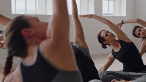 yoga class instructor teaching seated side bend pose group of multiracial women enjoying healthy lifestyle exercising in fitness studio meditation