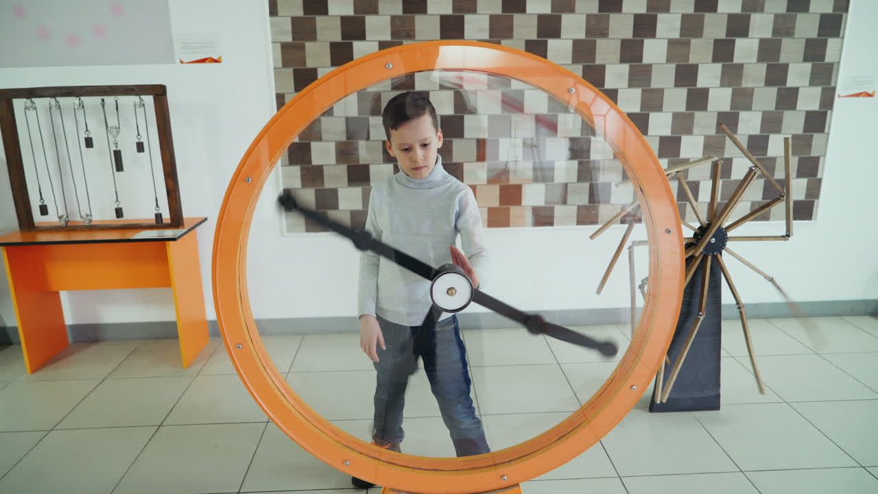 Child views the perpetual motion machine in the children's science museum. Boy in science center.