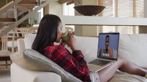 mixed race woman on laptop video chat having coffee at home