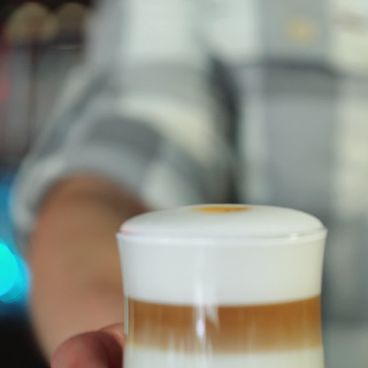 Barista gümüş bir sürahiden bardağa kahve döküyor, mükemmel bir latte bardağı. Kare video.