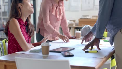 busy diverse architects discussing blueprints on table in office, slow motion