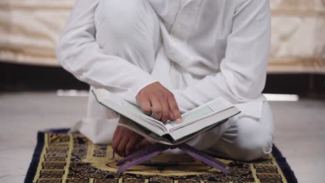 closeup of indian muslim man reading quran at home