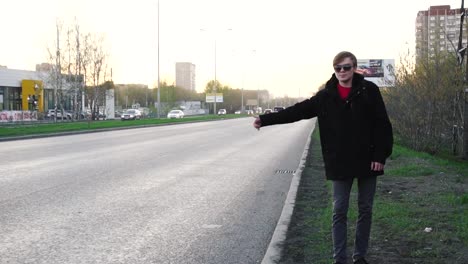 man hitchhiking on a city street