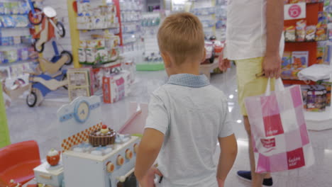 child is attracted with toy cooker in supermarket