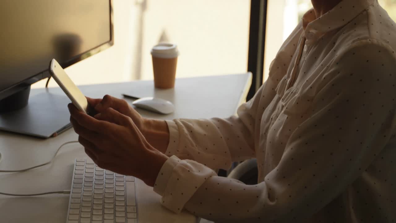 Businesswoman using mobile phone at desk 4k