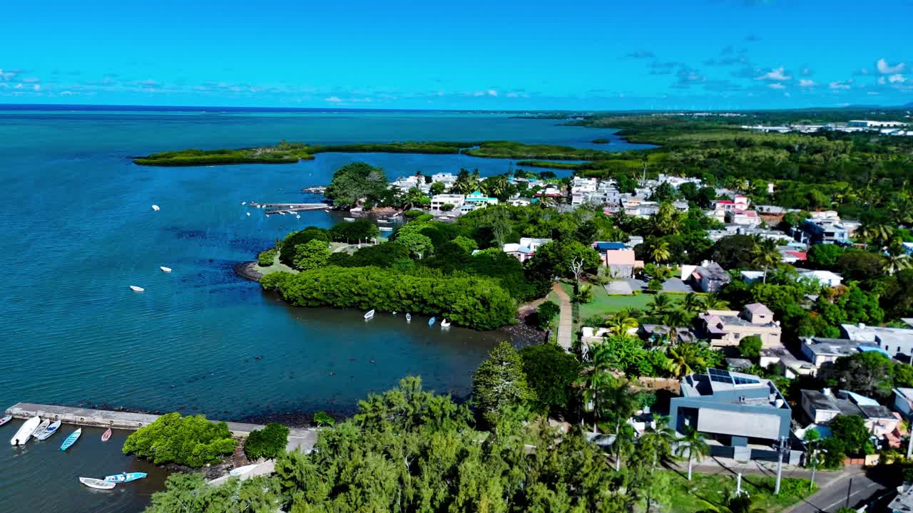 Coastal village and ocean inlet in Mauritius from high above, lush greenery meets bright shoreline