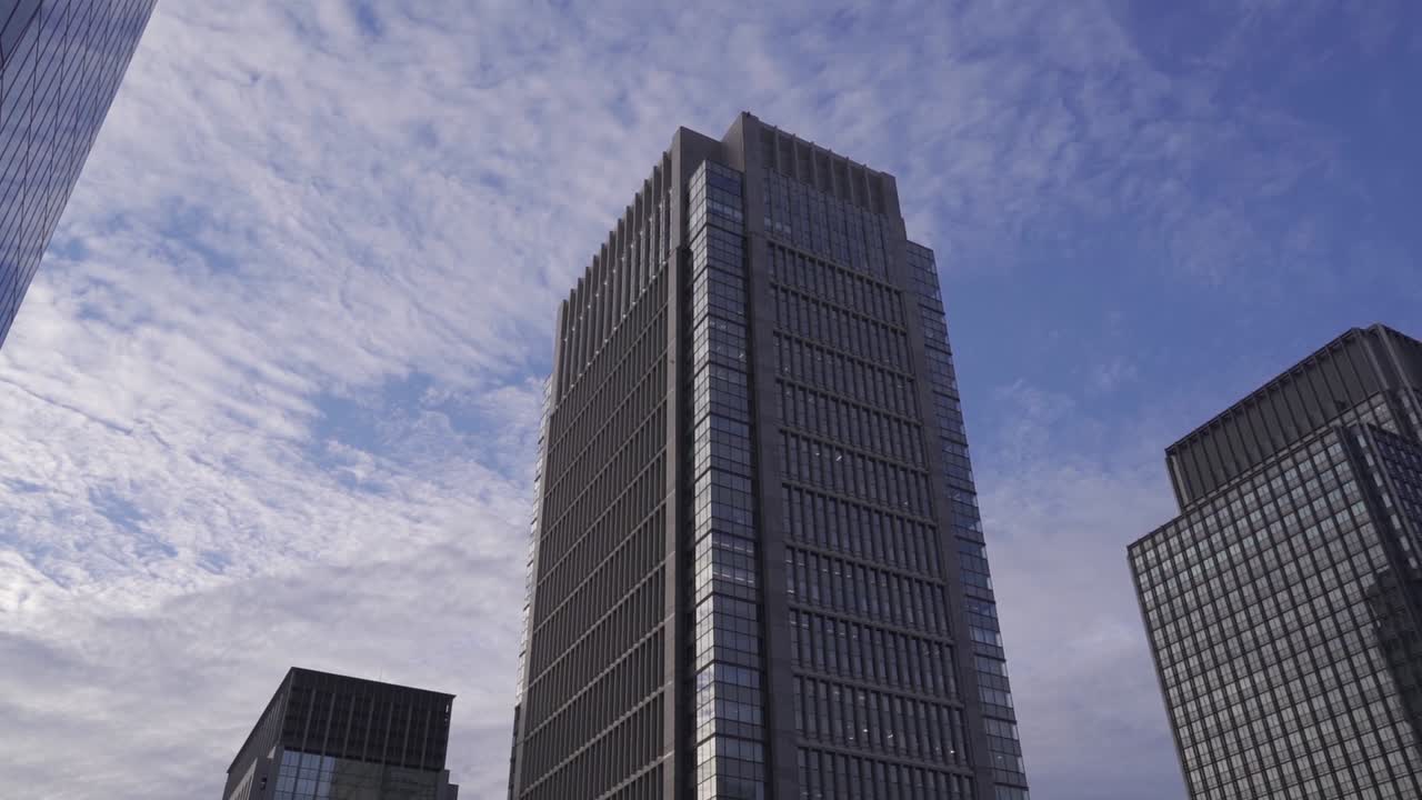 incline lentamente hacia rascacielos altos contra el hermoso cielo azul y nublado